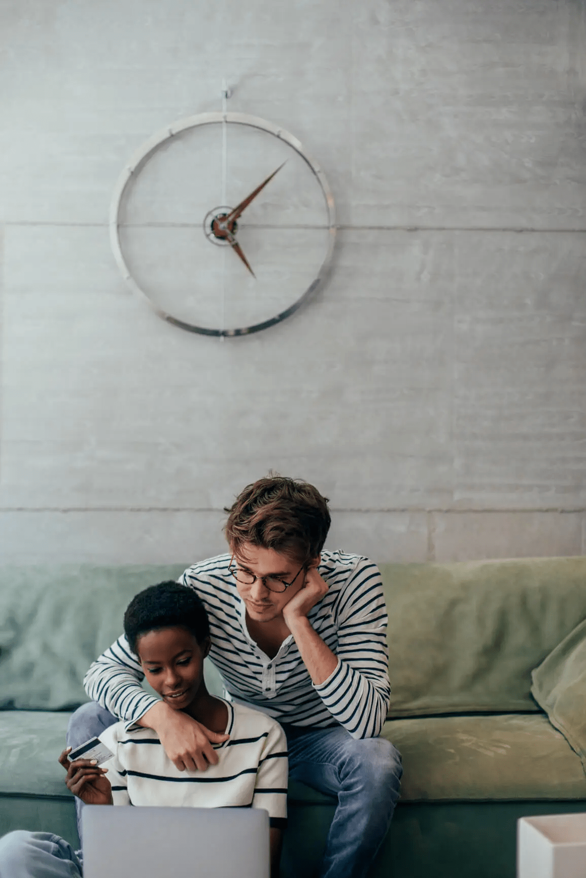 Couple looking at laptop while smiling and holding a credit card