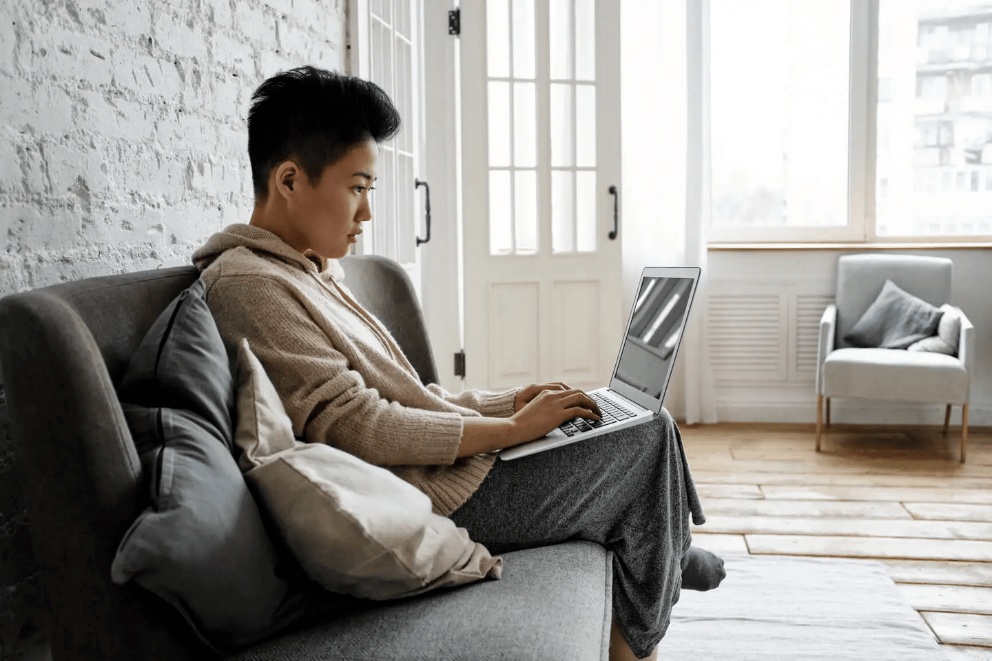 A woman typing on a laptop while sitting on a couch