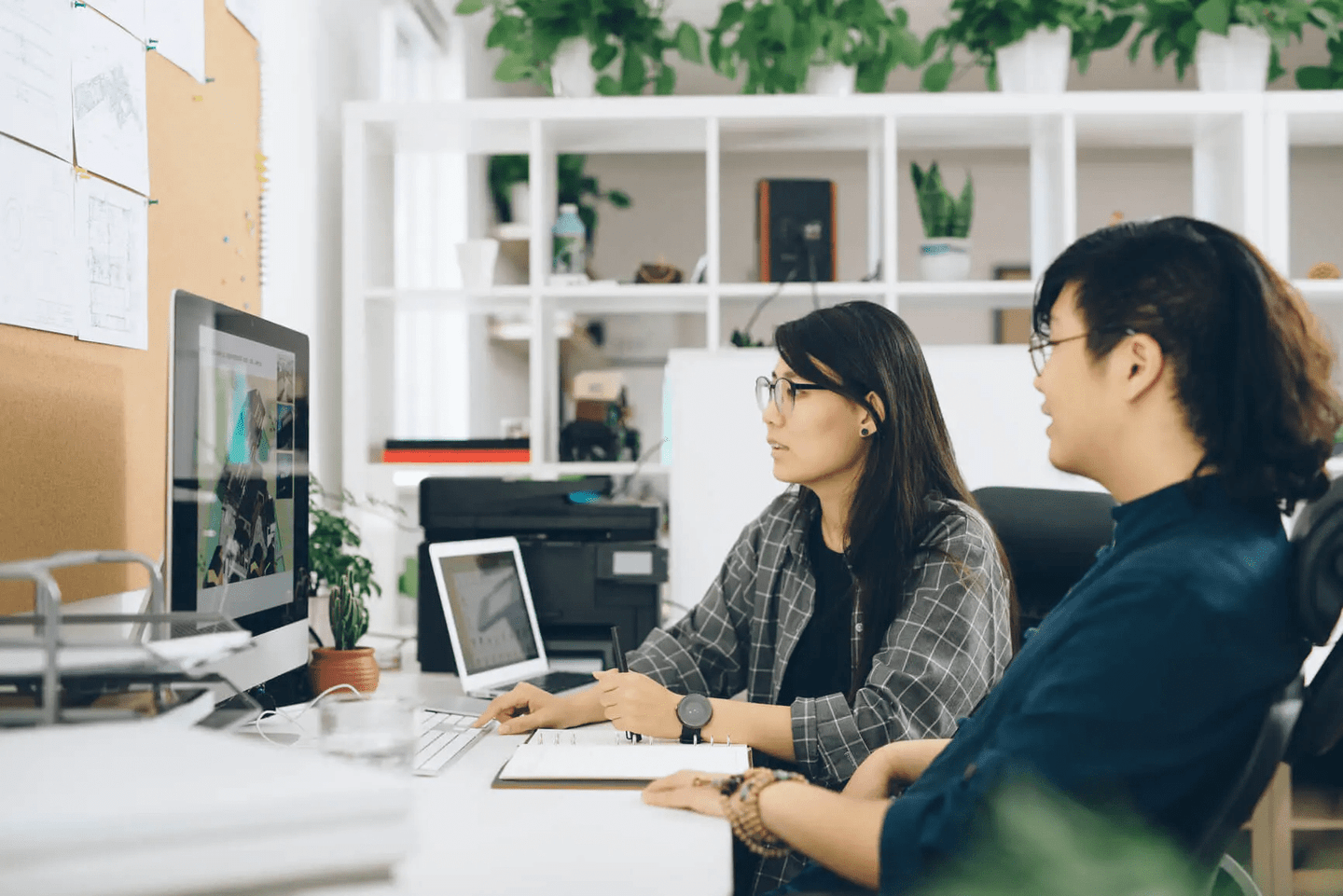 two people sitting around a laptop smiling