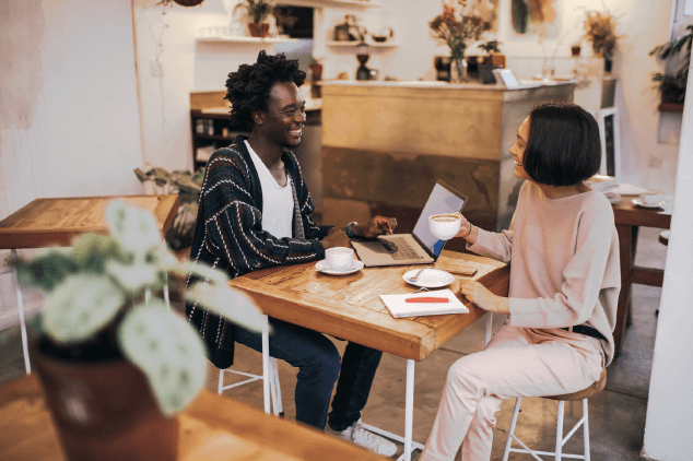 Two people at a coffee shop smiling at each other