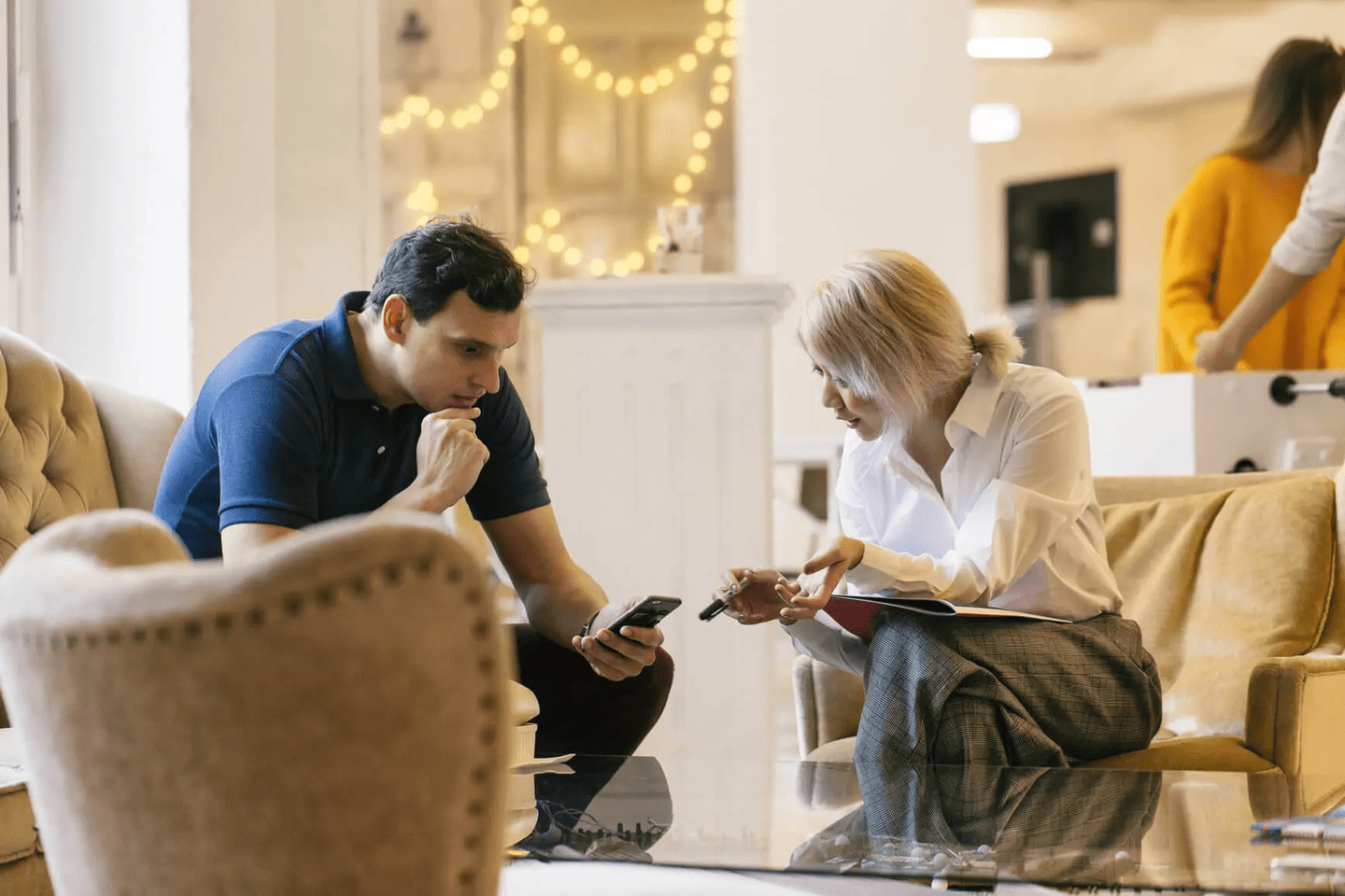 Two people talking while looking at phone