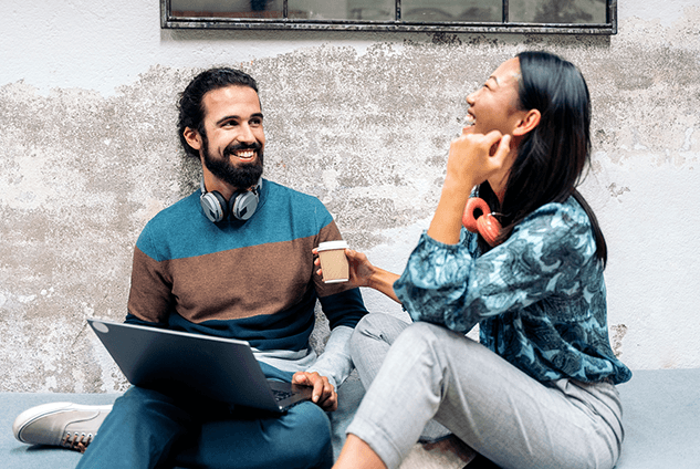 Two people around a laptop laughing