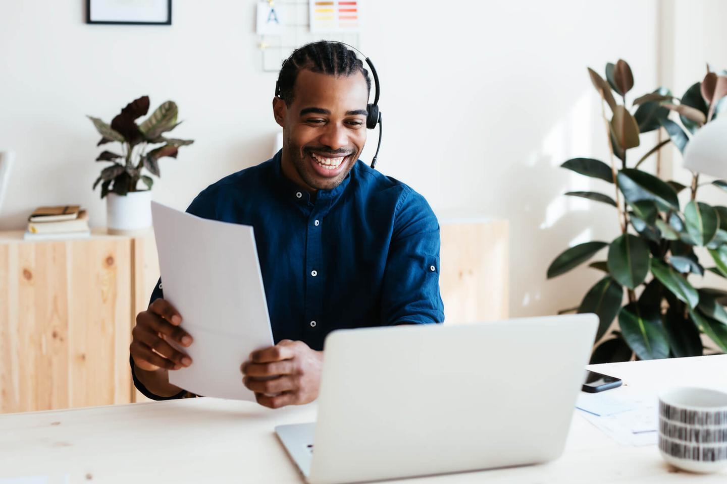 Man holding papers and smiling at laptop