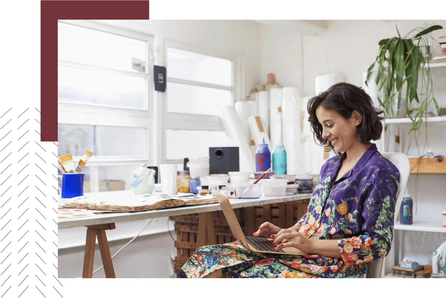 Woman in a colorful shirt happily working on her laptop