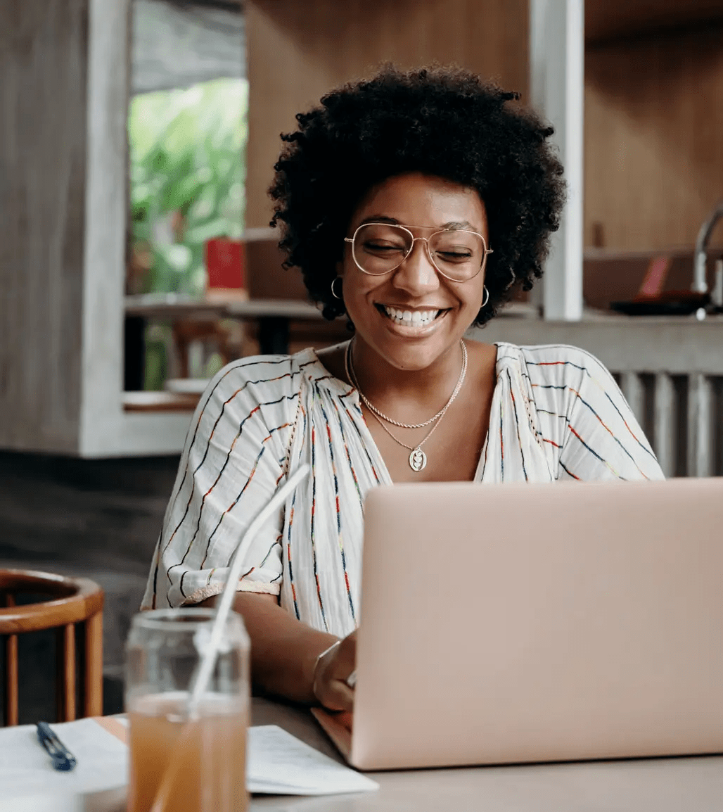 woman leaning on desk smiling with latop behind her